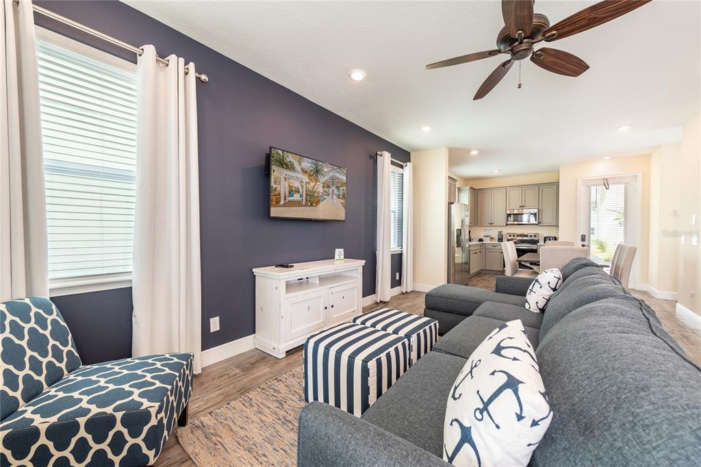 A living room features a dark blue accent wall, a gray sectional sofa, and an open kitchen — 2952 SALTED RIM ROAD, KISSIMMEE, FL