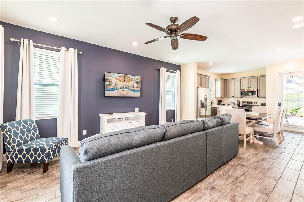 A living room with a dark blue accent wall, gray sofa, and an open kitchen — 2952 SALTED RIM ROAD, KISSIMMEE, FL