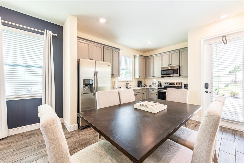 A dining area with a dark wooden table sits adjacent to a kitchen with gray cabinets — 2952 SALTED RIM ROAD, KISSIMMEE, FL