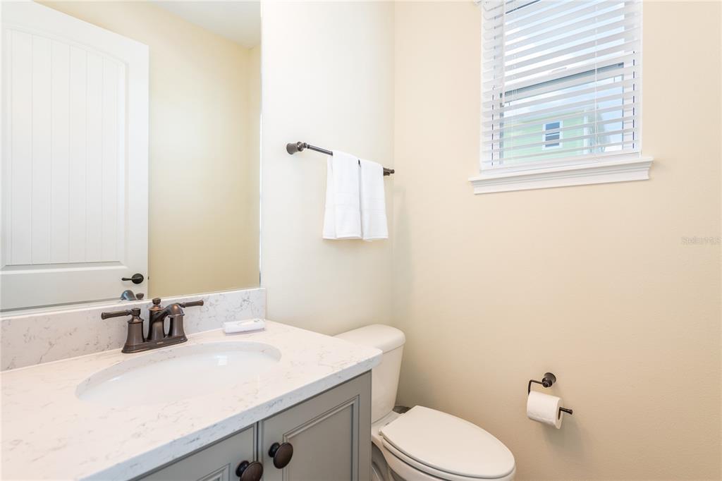 A bathroom features a gray vanity with a white countertop, a toilet, and a window — 2952 SALTED RIM ROAD, KISSIMMEE, FL