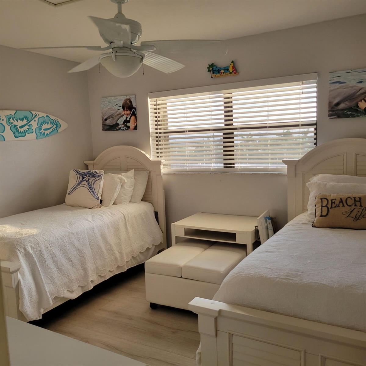 A bedroom with two white twin beds, a central table, and beach-themed wall decor — 10310 S Ocean Drive # 507, Jensen Beach FL 34957, JENSEN BEACH, FL