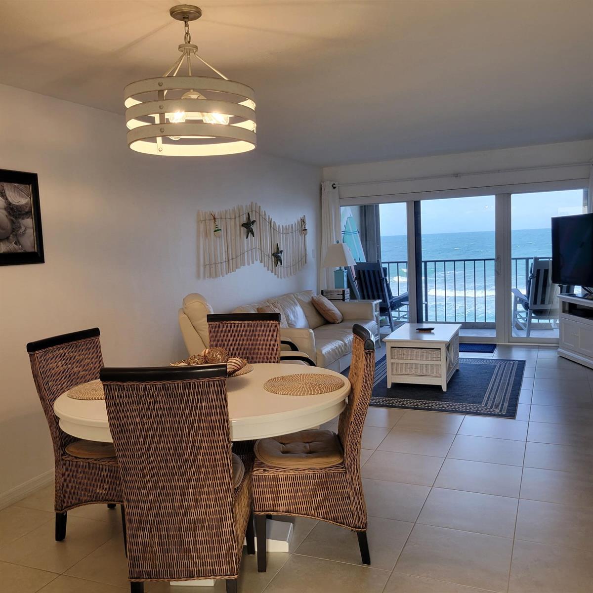 A dining area and living room overlook the ocean through large sliding glass doors — 10310 S Ocean Drive # 507, Jensen Beach FL 34957, JENSEN BEACH, FL