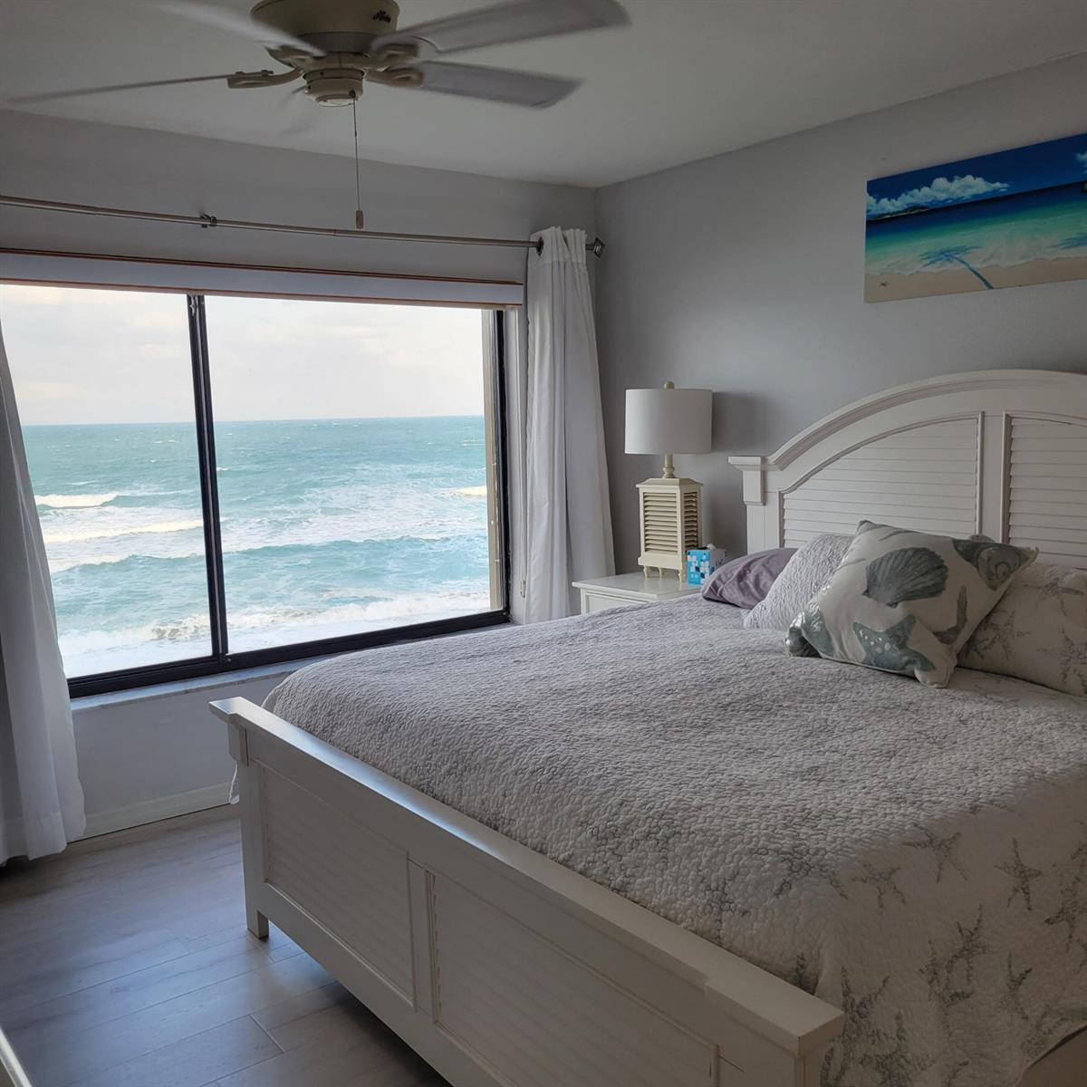 A bedroom with a white bed frame and a large window overlooking the ocean — 10310 S Ocean Drive # 507, Jensen Beach FL 34957, JENSEN BEACH, FL