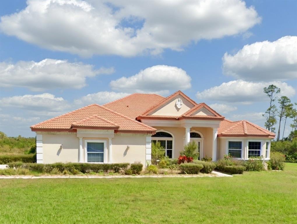 A single-story house with a tile roof and beige stucco exterior sits on a lawn — 9110 DEER COURT, VENICE, FL