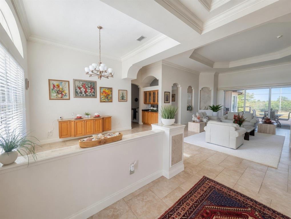 A bright, open-concept living area features tile floors, a half-wall divider, and a tray ceiling — 9110 DEER COURT, VENICE, FL