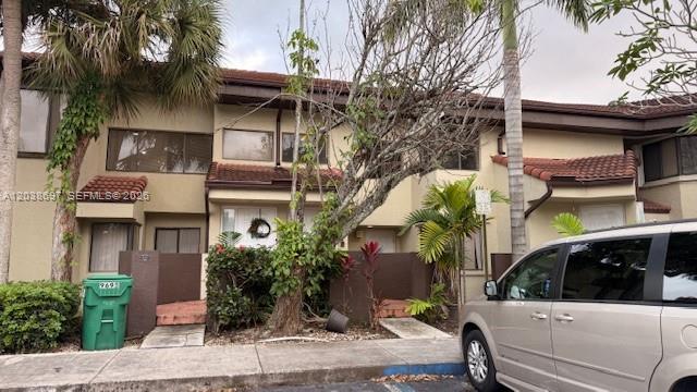 A multi-story townhouse exterior features tan stucco walls, brown trim, and a green trash bin — 9691 SW 138th Ave, Miami FL 33186, MIAMI, FL