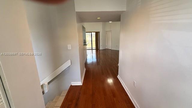 A hallway with hardwood flooring leads toward a living area with a sliding glass door — 9691 SW 138th Ave, Miami FL 33186, MIAMI, FL