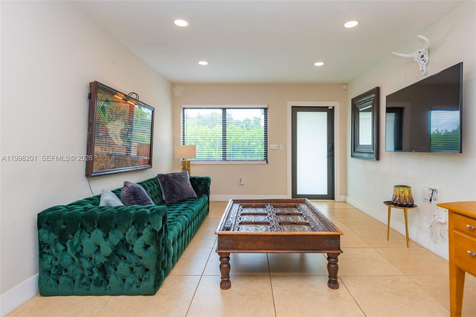 A living room features a green tufted sofa, a wooden coffee table, and a wall-mounted television — 2925 NW 11th Ave, Miami FL 33127, MIAMI, FL