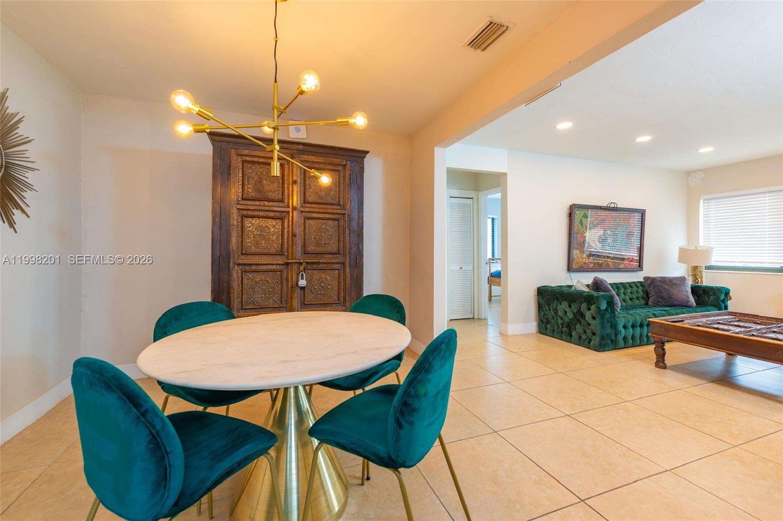 A dining area with a round table and velvet chairs sits beside a living room — 2925 NW 11th Ave, Miami FL 33127, MIAMI, FL