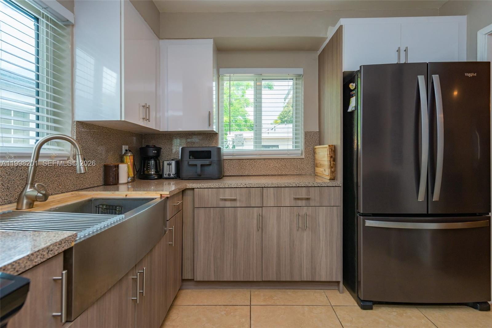 A kitchen features wood-grain lower cabinets, white upper cabinets, a farmhouse sink, and dark appliances — 2925 NW 11th Ave, Miami FL 33127, MIAMI, FL