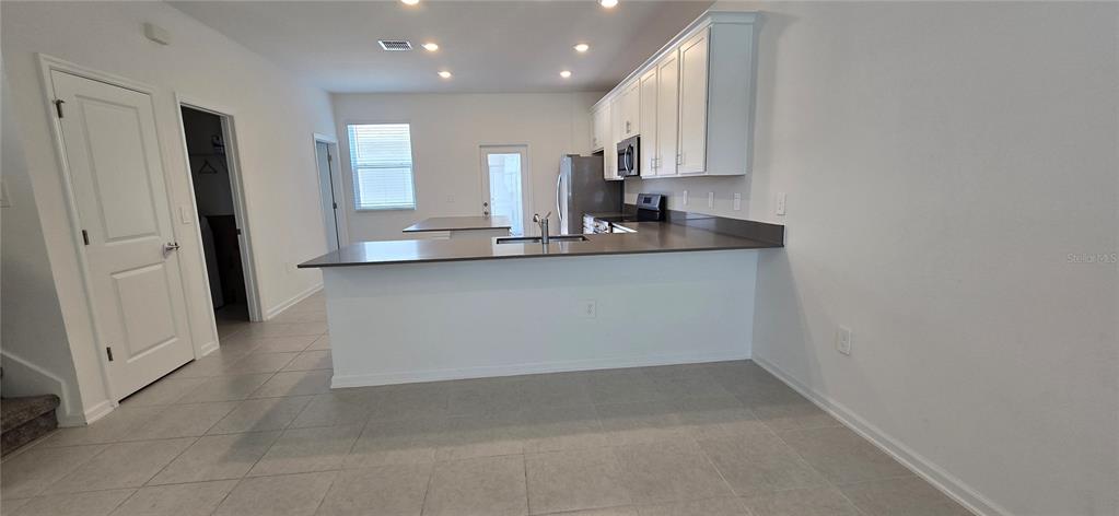 A kitchen features white cabinets, dark countertops, a breakfast bar, and light-colored tile flooring — 2012 TOHOQUA BOULEVARD, KISSIMMEE, FL