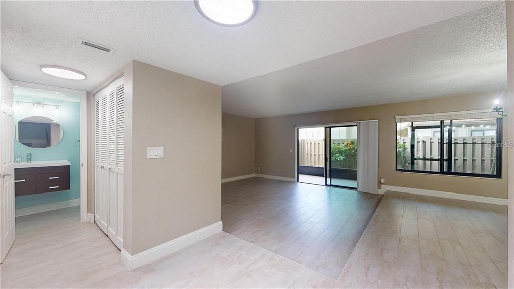 An open-concept living area features light-colored tile flooring, a sliding glass door, and a bathroom — 202 PINE CONE TRAIL, ORMOND BEACH, FL
