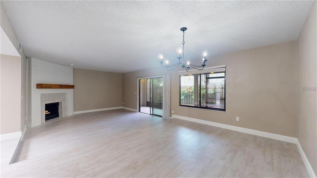 A living room features light wood-look tile flooring, a fireplace with a mantel, and a chandelier — 202 PINE CONE TRAIL, ORMOND BEACH, FL