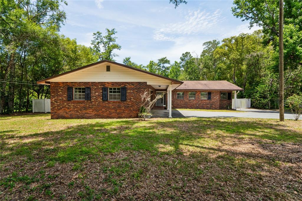 A single-story brick house with a covered entryway and a large, tree-lined front yard — 1022 S MILDRED AVENUE, BROOKSVILLE, FL
