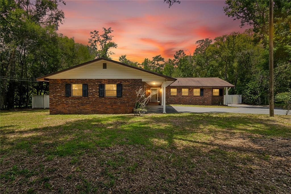 A single-story brick house with a covered entryway stands before a sunset sky — 1022 S MILDRED AVENUE, BROOKSVILLE, FL