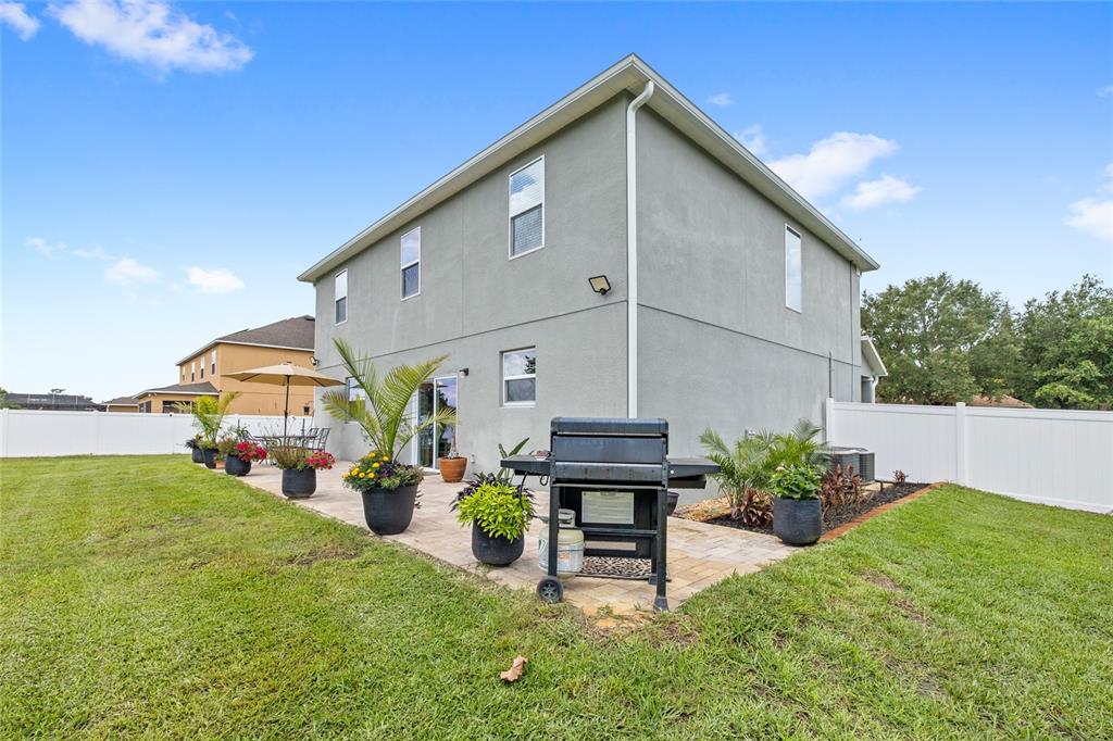 A backyard patio features a grill, potted plants, and a white fence against a house — 122 LOS ARBOR DRIVE, DELAND, FL