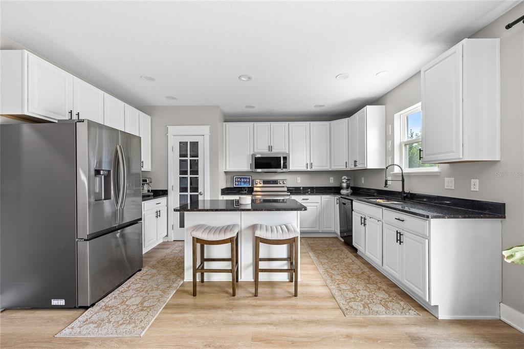 A kitchen features white cabinets, dark countertops, stainless steel appliances, and a central island — 122 LOS ARBOR DRIVE, DELAND, FL