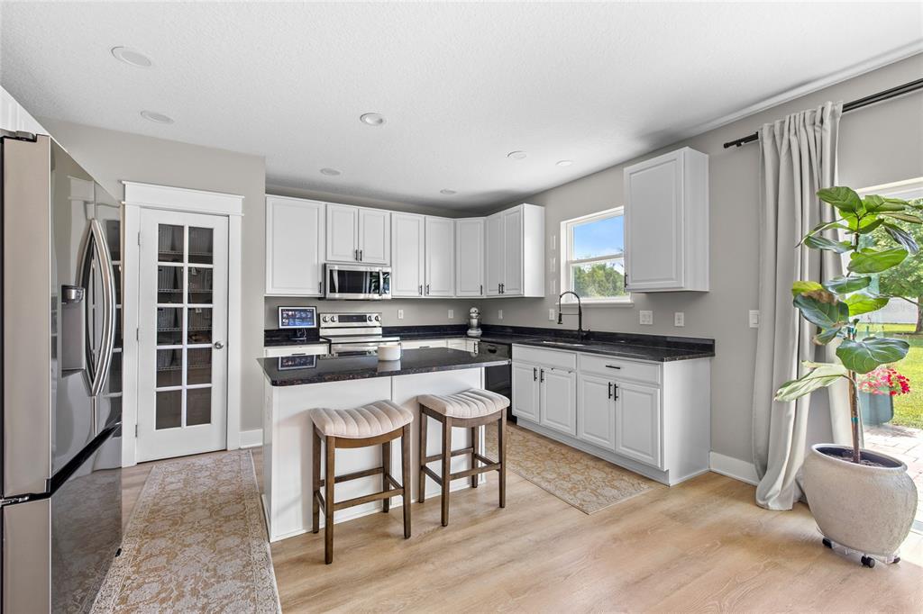 A kitchen with white cabinets, dark countertops, a center island with stools, and light flooring — 122 LOS ARBOR DRIVE, DELAND, FL
