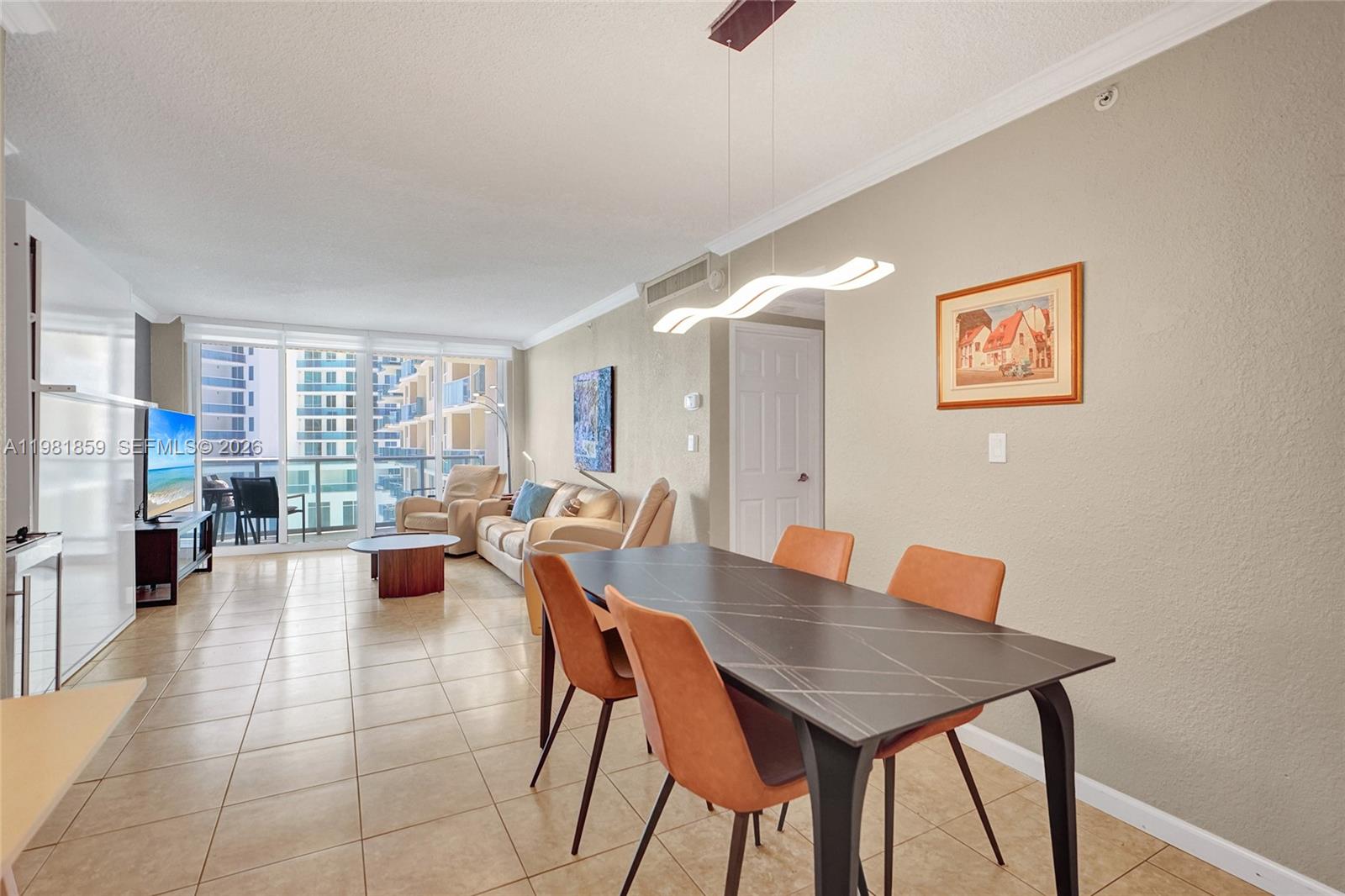 A dining area with a modern table and chairs leads into a living room — 2501 S Ocean Dr, Hollywood FL 33019, HOLLYWOOD, FL