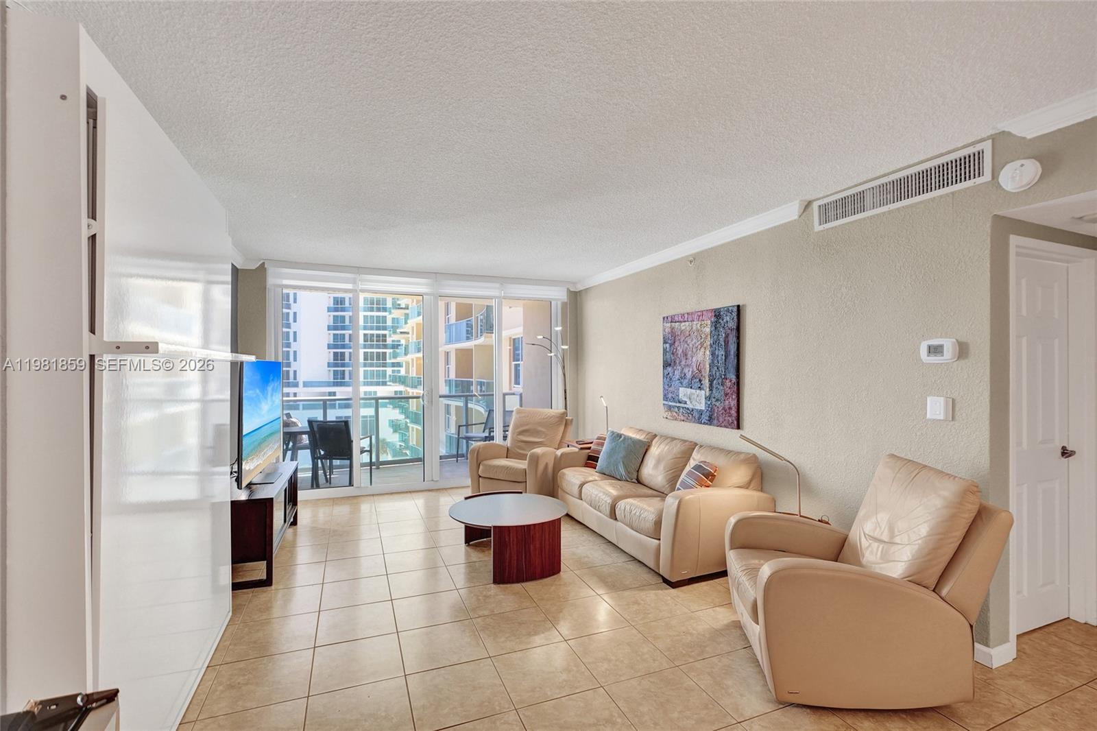 A living room features beige tile floors, a leather sofa, two armchairs, and a balcony — 2501 S Ocean Dr, Hollywood FL 33019, HOLLYWOOD, FL