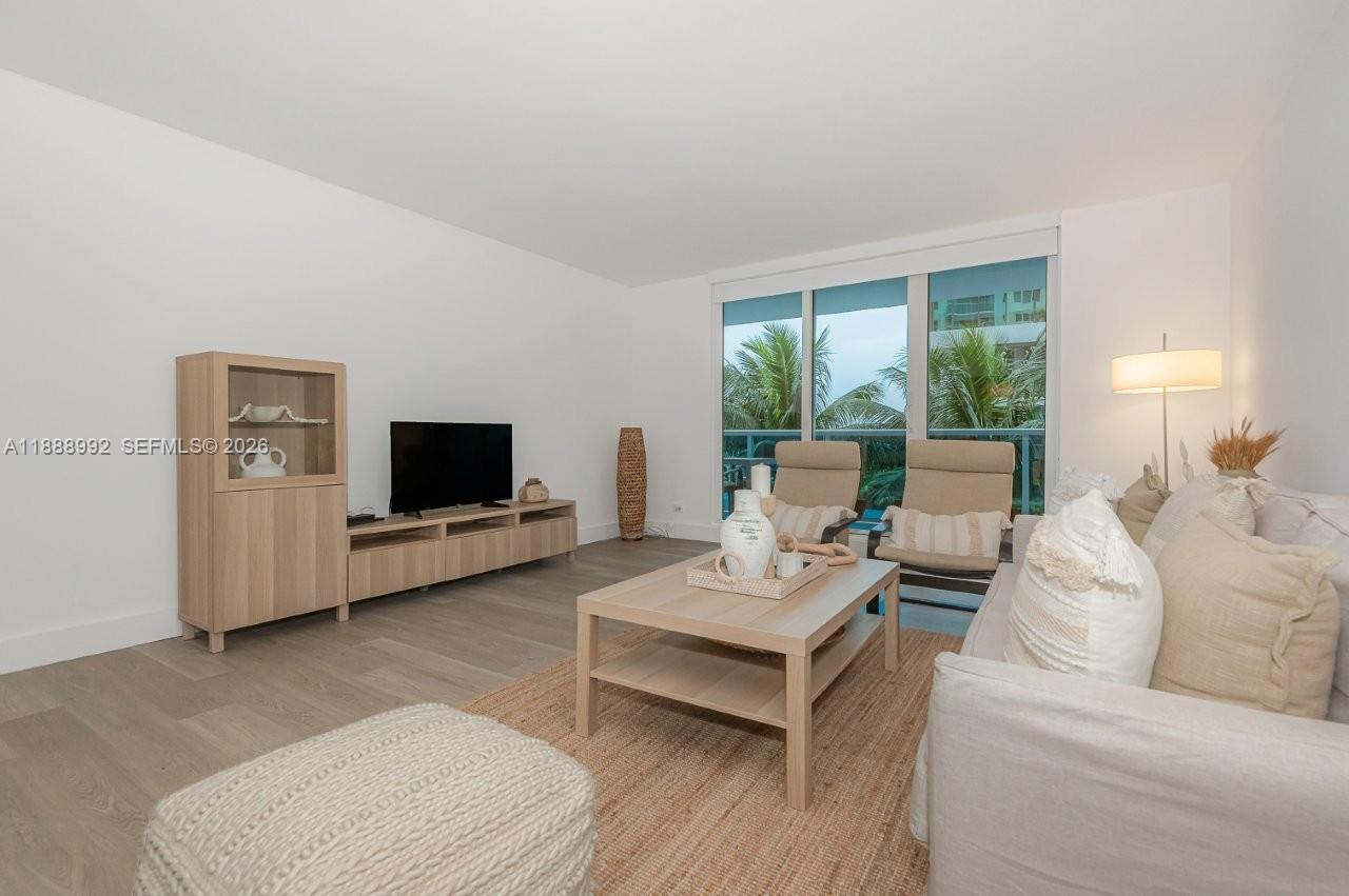 A living room features light wood furniture, a beige sofa, and a large sliding glass door — 2301 Collins Ave # 333, Miami Beach FL 33139, MIAMI BEACH, FL