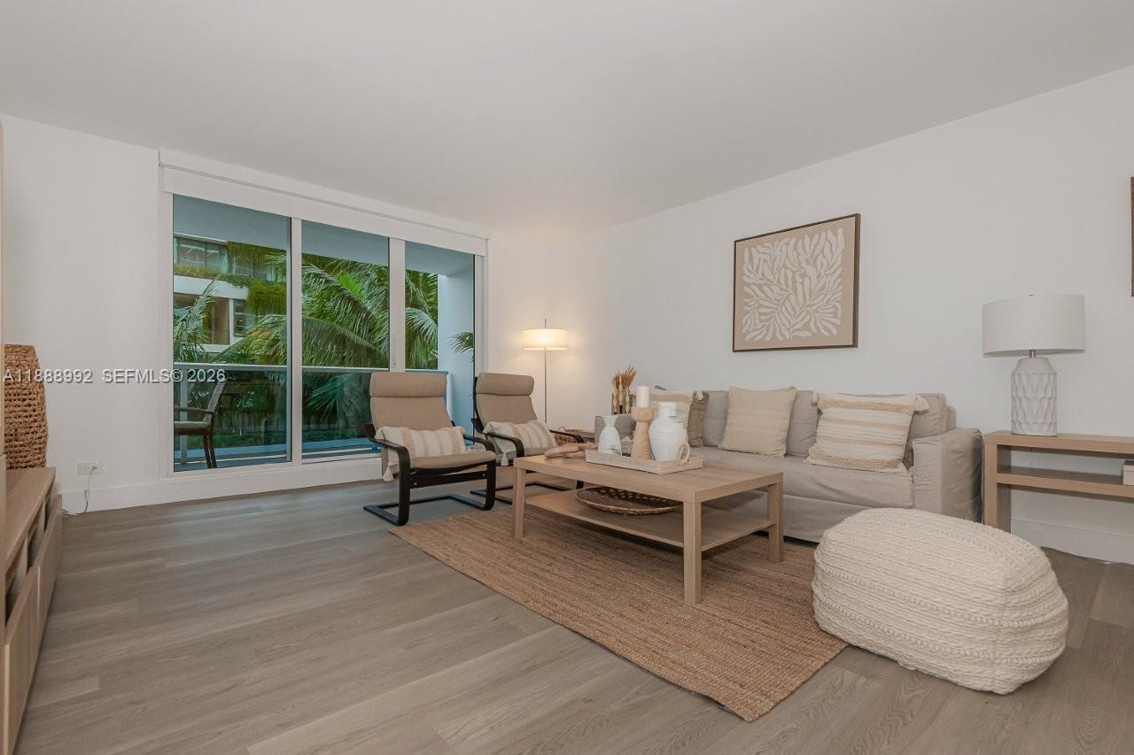 A living room features light wood flooring, a beige sofa, two armchairs, and a balcony — 2301 Collins Ave # 333, Miami Beach FL 33139, MIAMI BEACH, FL