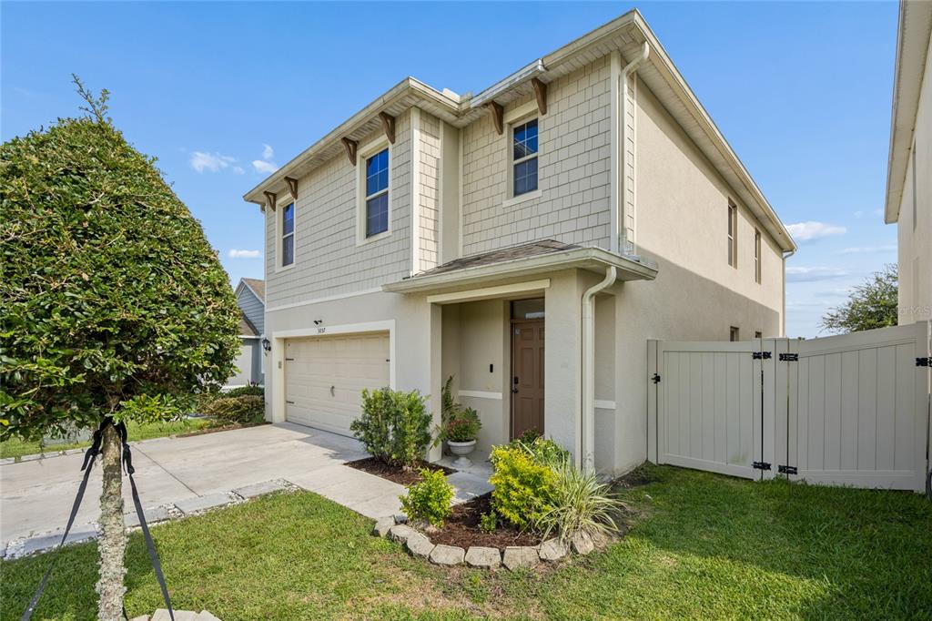 A two-story house with a beige stucco exterior, a single-car garage, and a white fence — 3057 TIMBER HAWK CIRCLE, OCOEE, FL