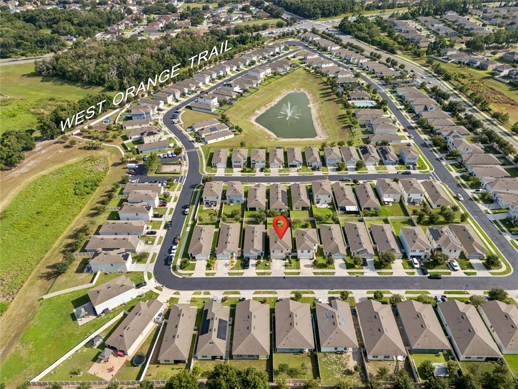 Aerial view of a suburban neighborhood featuring a central pond and a nearby trail — 3057 TIMBER HAWK CIRCLE, OCOEE, FL