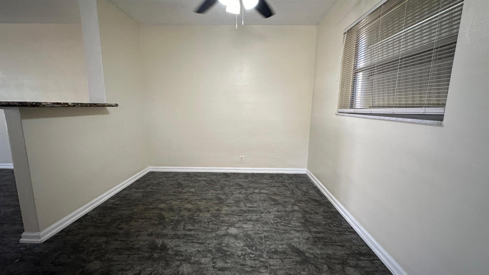 An empty dining area features beige walls, a ceiling fan, and dark gray tile flooring — 1973 #1 NE 4th Street, Deerfield Beach FL 33441, DEERFIELD BEACH, FL