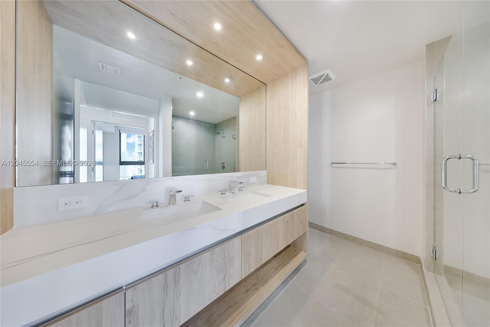 A modern bathroom features a double vanity with light wood cabinetry and marble countertops — 11 NE 6th St # 3209, Miami FL 33132, MIAMI, FL