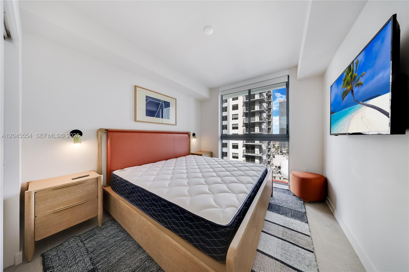 A bedroom features a bed with an orange headboard, a wall-mounted television, and city views — 11 NE 6th St # 3209, Miami FL 33132, MIAMI, FL