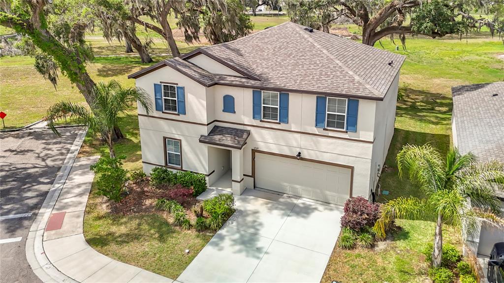 An aerial view of a two-story suburban house with a tan stucco exterior and garage — 6969 FABEN LANE, ZEPHYRHILLS, FL