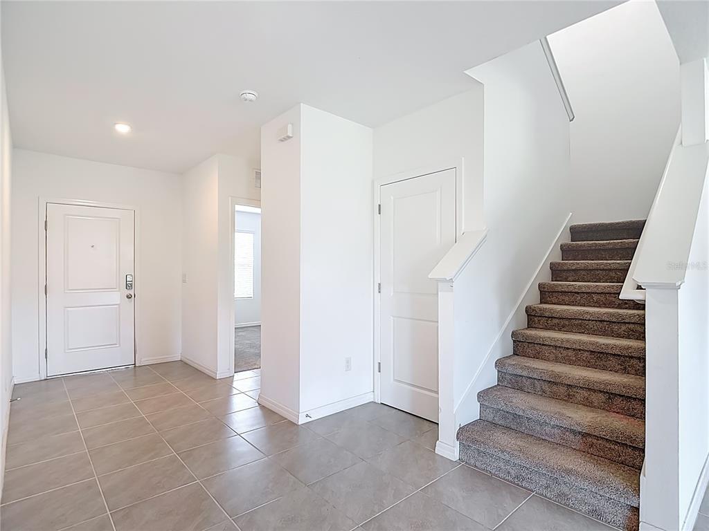 An entryway features tile flooring, a white front door, a staircase, and a closet door — 6969 FABEN LANE, ZEPHYRHILLS, FL