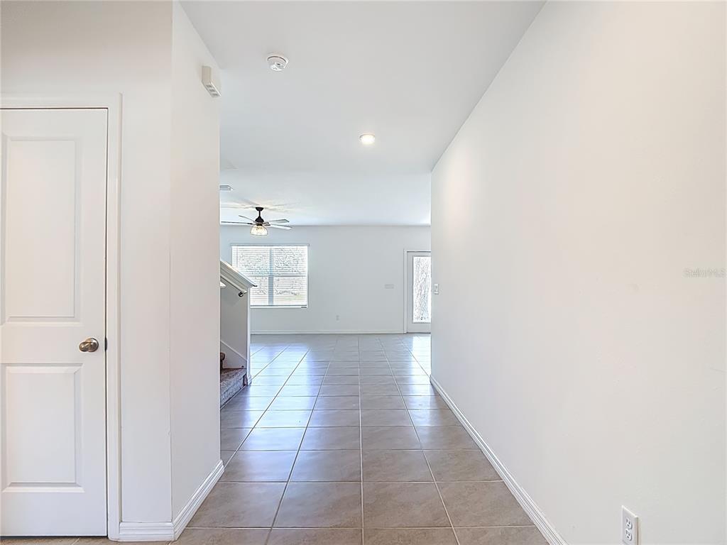 A tiled hallway leads to an open living area with a staircase and ceiling fan — 6969 FABEN LANE, ZEPHYRHILLS, FL