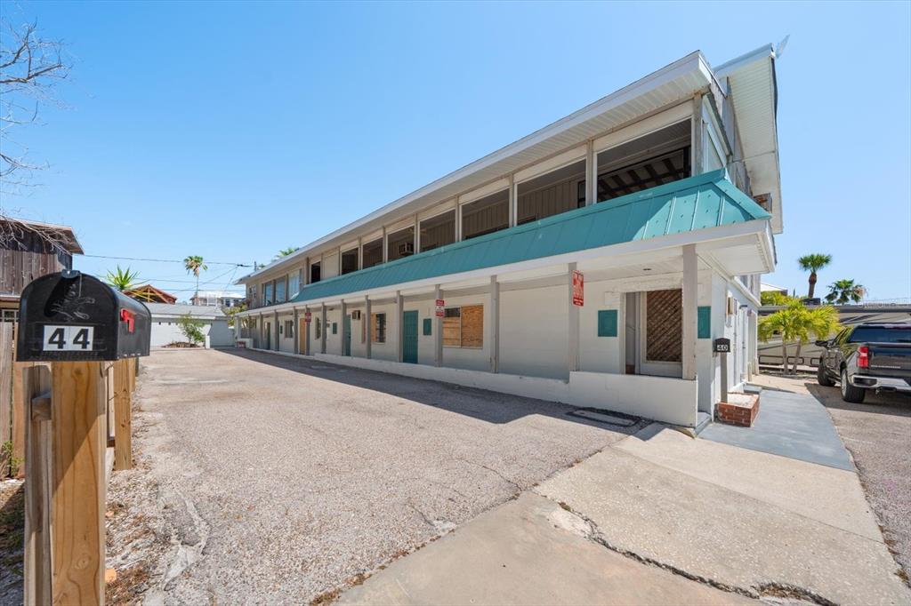 An exterior view of a two-story motel building with a gravel parking lot — 40 77TH AVENUE, TREASURE ISLAND, FL