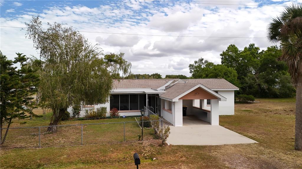 A single-story house with a white exterior, a covered carport, and a fenced front yard — 6386 SCOTT STREET, PUNTA GORDA, FL