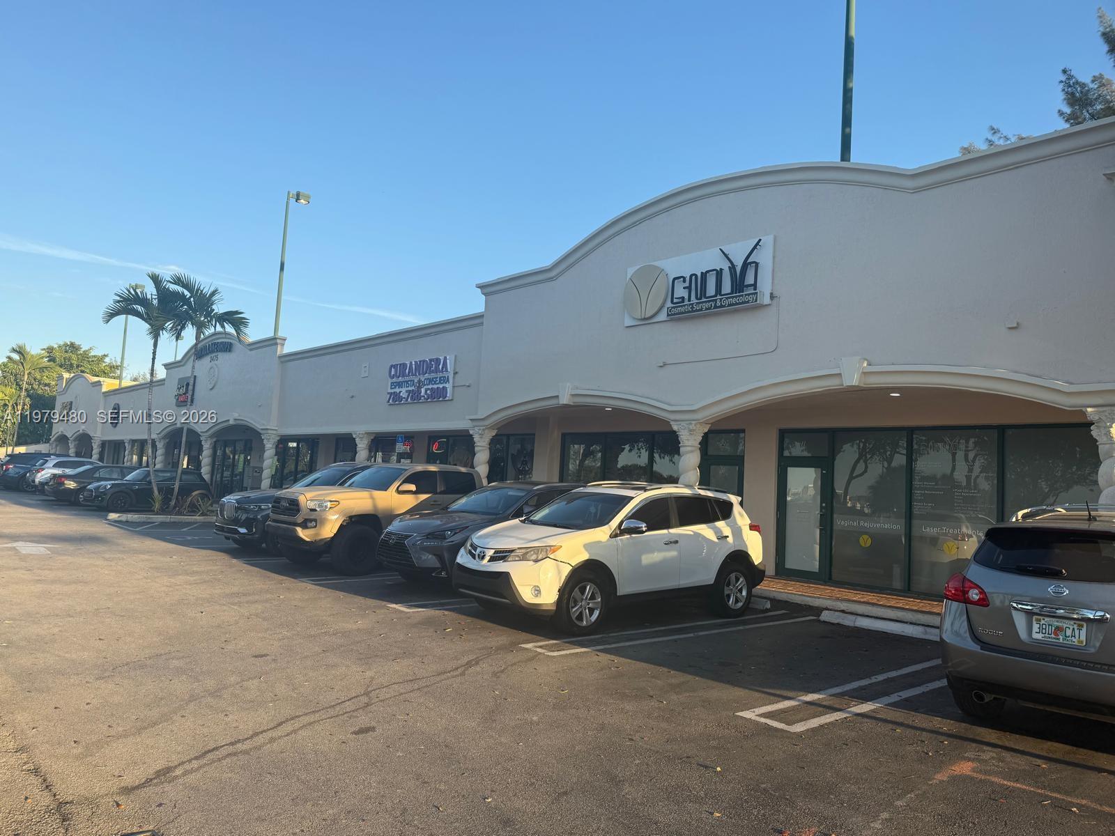 A row of commercial storefronts with parked cars in front under a clear blue sky — 2475 NW 95th Ave # 2, Doral FL 33172, DORAL, FL