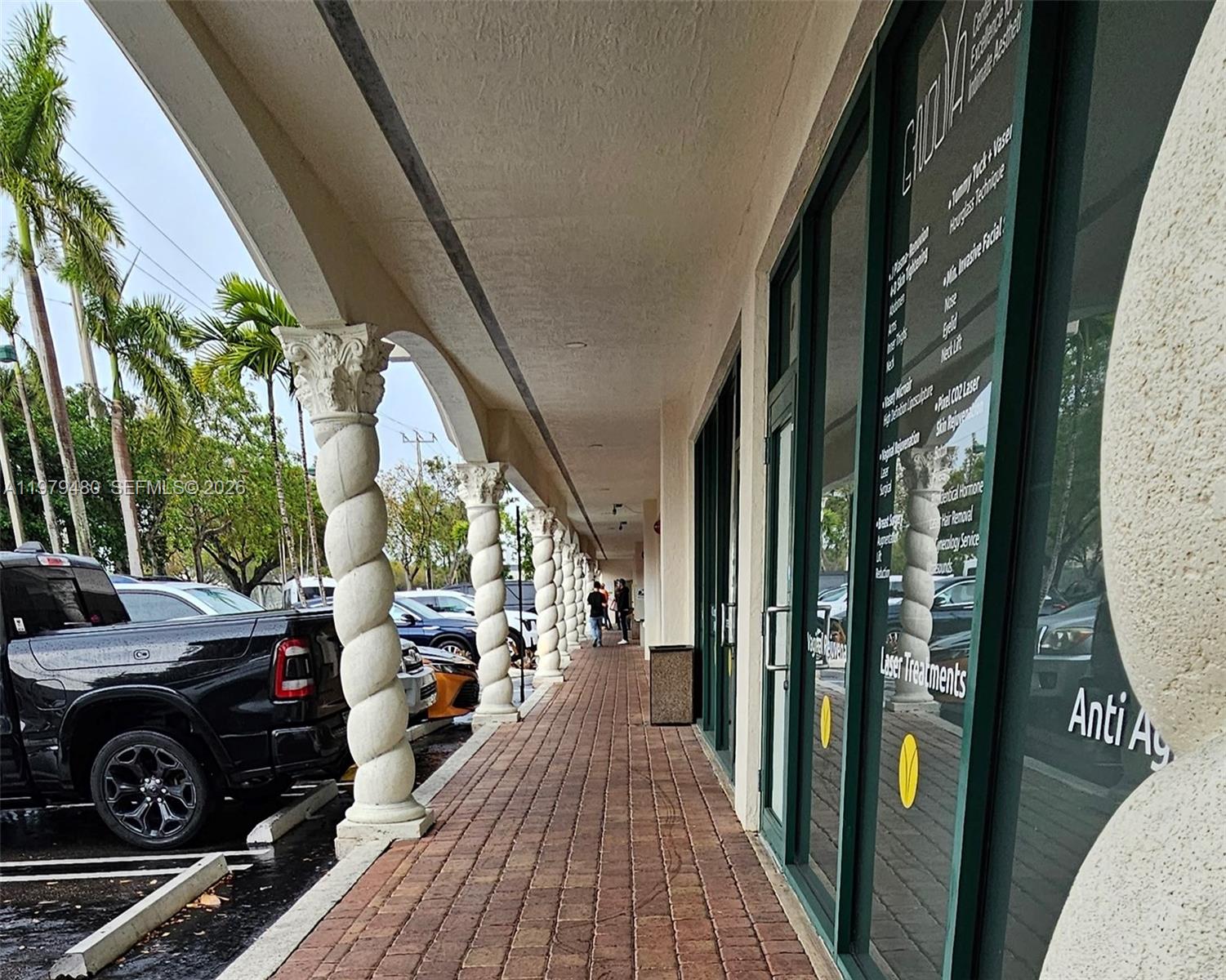 A covered walkway features decorative spiral columns and glass storefronts along a brick-paved path — 2475 NW 95th Ave # 2, Doral FL 33172, DORAL, FL