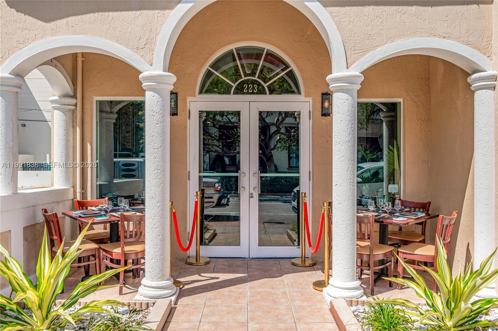 The exterior entrance features double glass doors, arched columns, and outdoor dining tables — 223 Valencia Ave, Coral Gables FL 33134, CORAL GABLES, FL