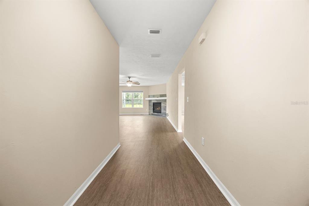 A hallway with light-colored walls and wood-look flooring leads toward a living room with a fireplace — 249 SW PLEASANT HILL GLEN, FORT WHITE, FL
