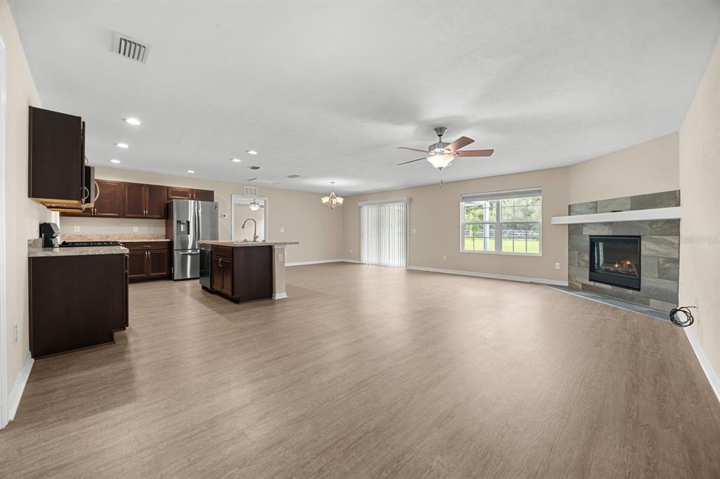 An open-concept living room and kitchen with dark wood cabinets, light flooring, and a fireplace — 249 SW PLEASANT HILL GLEN, FORT WHITE, FL