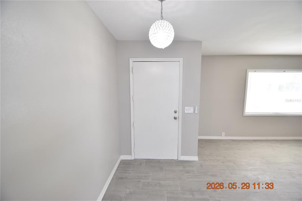 An entryway features a white door, gray tile flooring, and a crystal pendant light fixture — 4060 N LITTLE HAWK POINT, CRYSTAL RIVER, FL