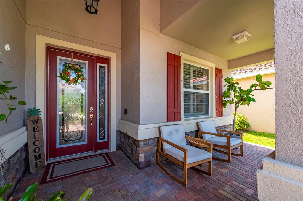 A front porch features a red door, two wooden chairs, and stone veneer accents — 3006 ORIOLE DRIVE, SARASOTA, FL