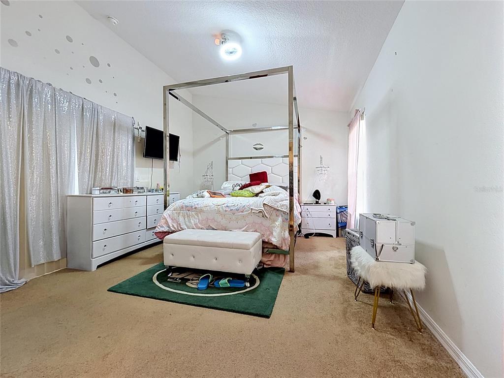 A bedroom features a metal canopy bed, white furniture, and a green rug on carpet — 230 HYPOLITA AVENUE, DAVENPORT, FL