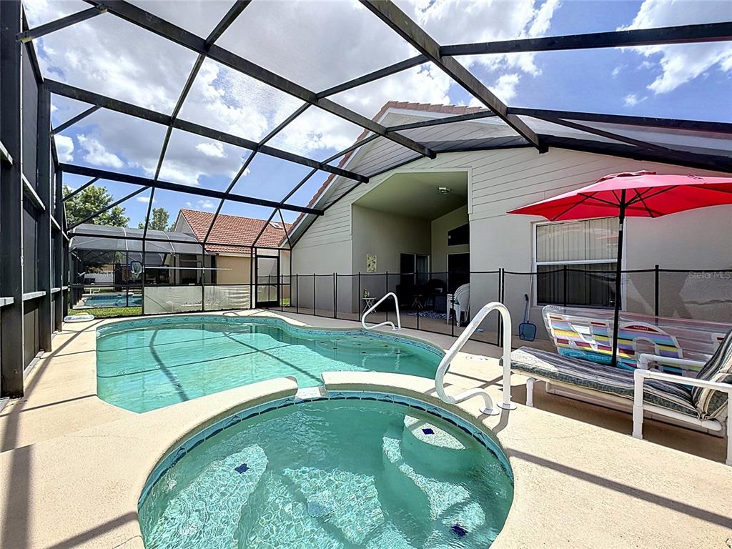 A screened-in patio features a swimming pool, a circular spa, and a red umbrella — 230 HYPOLITA AVENUE, DAVENPORT, FL