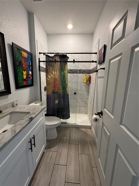 A bathroom features a white vanity, a toilet, and a walk-in shower with tiled walls — 515 5TH STREET S, DUNDEE, FL