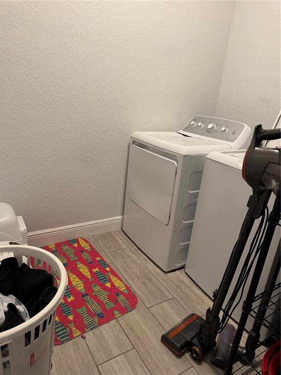 A laundry room features a washer, a dryer, a fish-patterned rug, and a laundry basket — 515 5TH STREET S, DUNDEE, FL