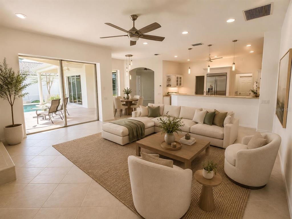 A bright open-concept living room features a sectional sofa, neutral decor, and sliding glass doors — 7468 ROXYE LANE, SARASOTA, FL
