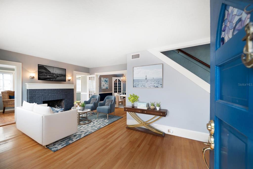A living room features hardwood floors, a blue brick fireplace, and a blue front door — 310 N LINCOLN AVENUE, CLEARWATER, FL