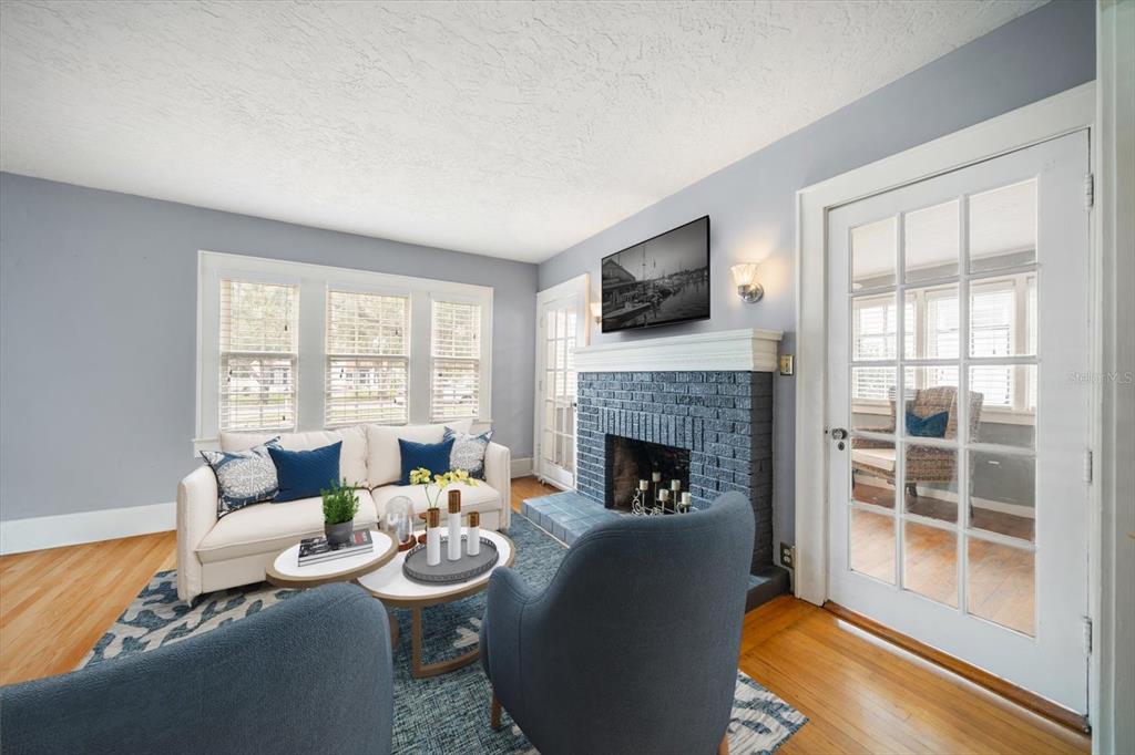 A living room features a blue brick fireplace, white sofa, and two blue armchairs — 310 N LINCOLN AVENUE, CLEARWATER, FL